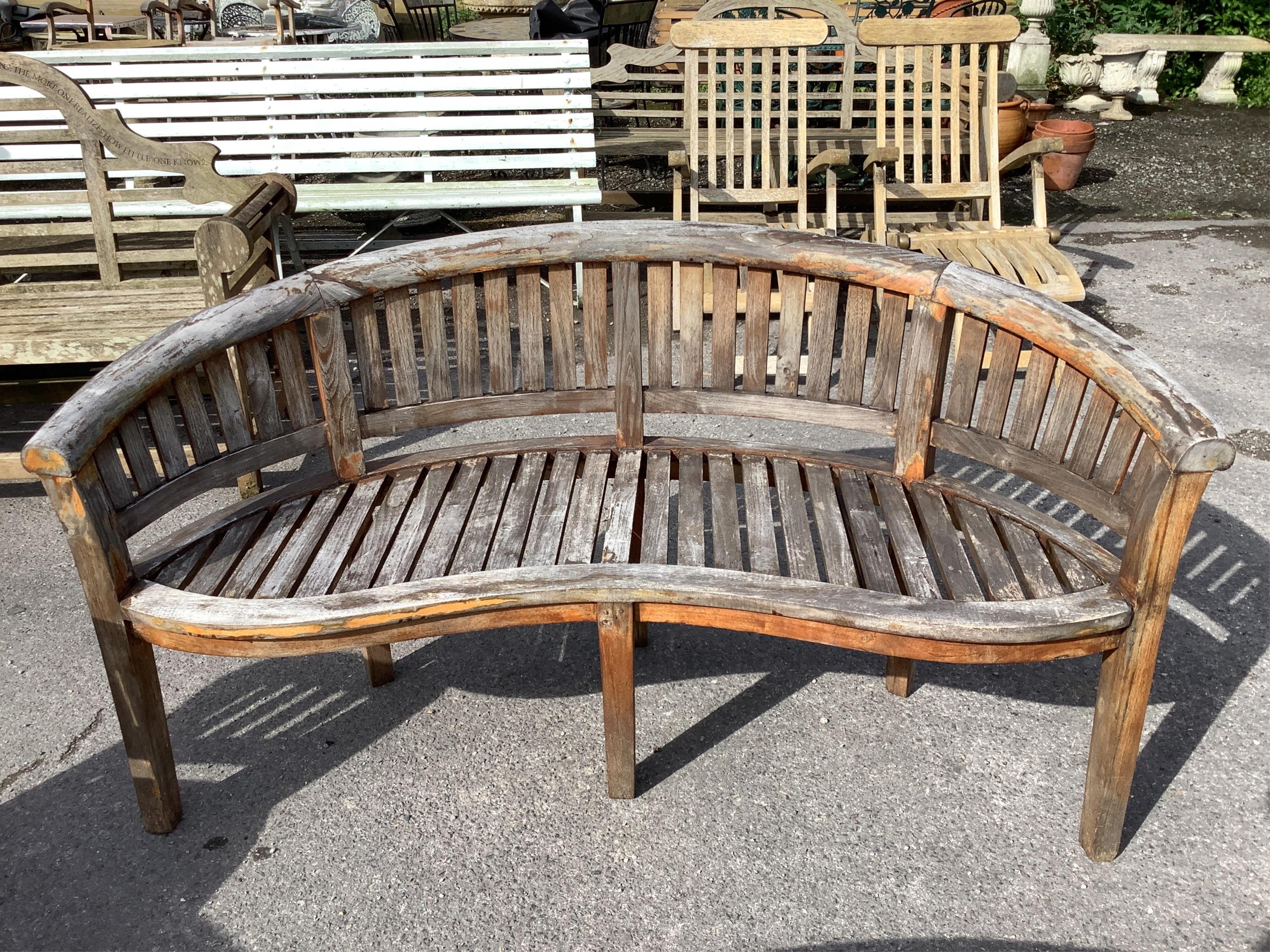 A weathered teak garden 'banana' bench, width 150cm, depth 60cm, height 84cm, a pair of chairs and coffee table